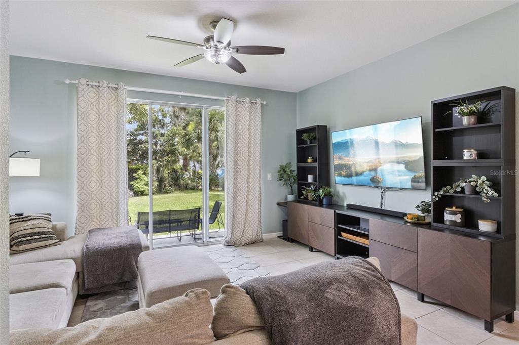 A living room features a sectional sofa, a wall-mounted television, and sliding glass patio doors — 5329 SYLVESTER LOOP, TAMPA, FL