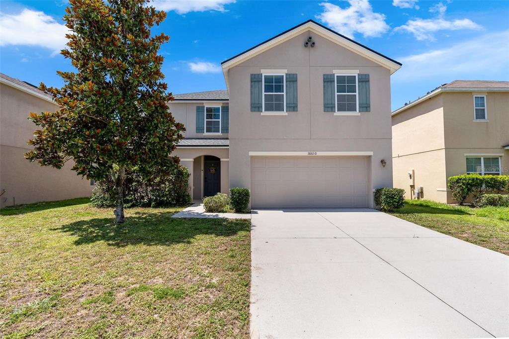 A two-story suburban house with a beige exterior, a two-car garage, and a front lawn — 16610 BROADFORD LANE, CLERMONT, FL