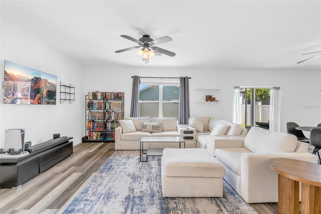 A living room features a white sectional sofa, a patterned rug, and a television console — 16610 BROADFORD LANE, CLERMONT, FL