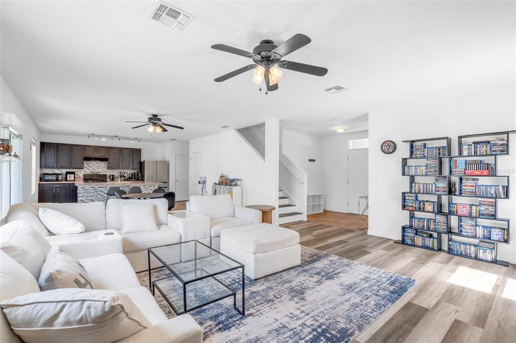 A living room with a white sectional sofa, glass coffee table, and a large media shelf — 16610 BROADFORD LANE, CLERMONT, FL
