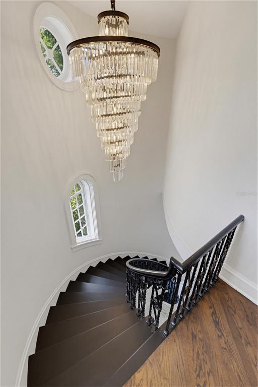 A spiral staircase with dark wood steps and a black metal railing under a crystal chandelier — 190 BOSPHOROUS AVENUE, TAMPA, FL