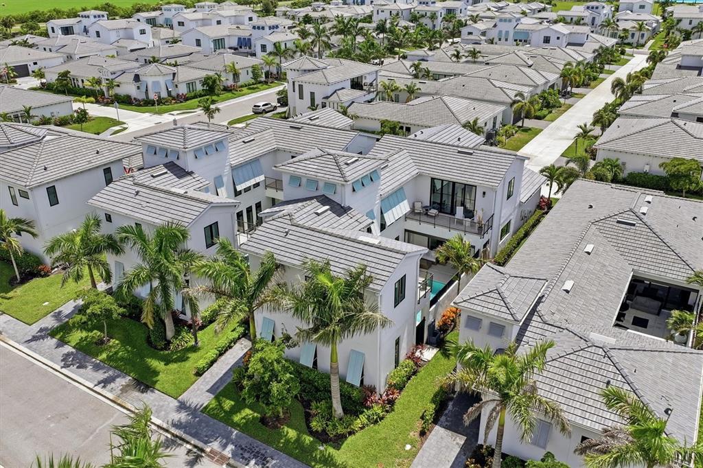 An aerial view shows a modern white house with a gray tile roof and palm trees — 5935 REDBAY BOULEVARD, BRADENTON, FL