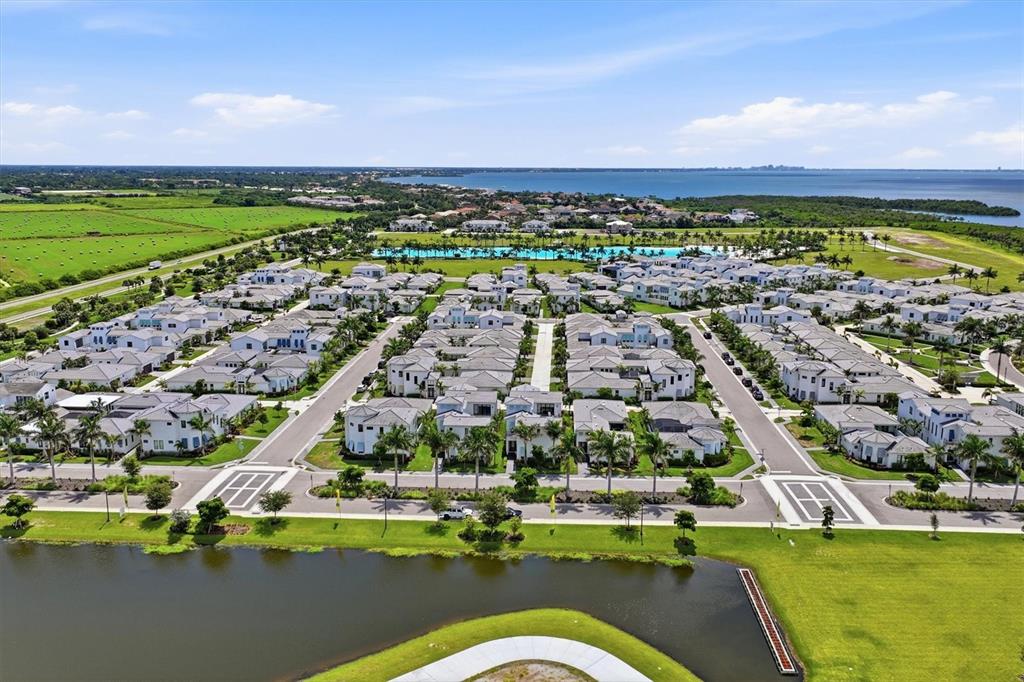 An aerial view shows a residential community with numerous houses, a central pool, and a lake — 5935 REDBAY BOULEVARD, BRADENTON, FL