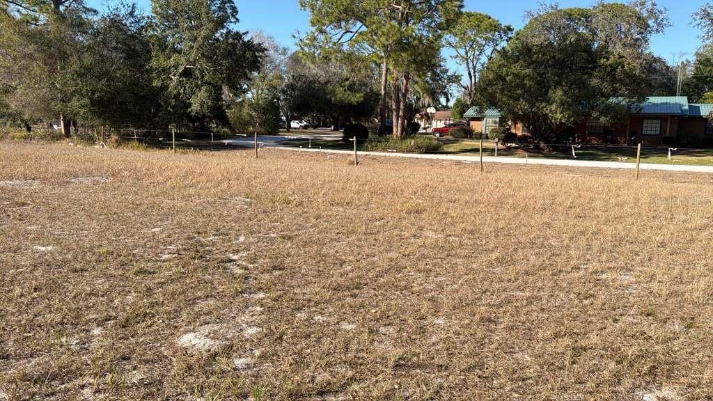 A vacant, grassy lot with a wire fence and trees in the background — 0 N KRAFT ROAD, AVON PARK, FL