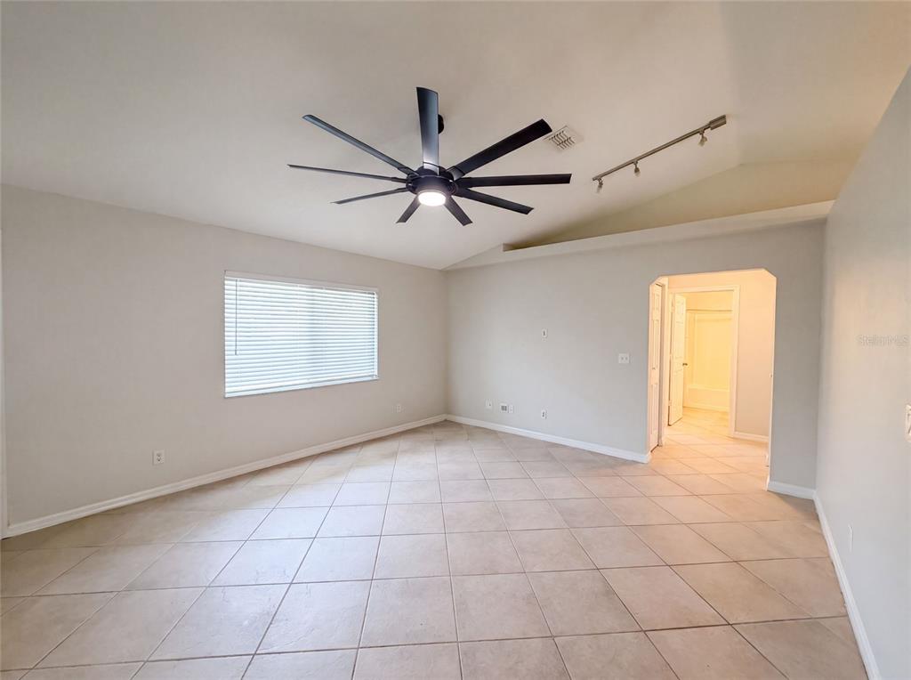 An empty room with light-colored tile flooring, a ceiling fan, and a vaulted ceiling — 1719 NEEDLE PALM DRIVE, EDGEWATER, FL