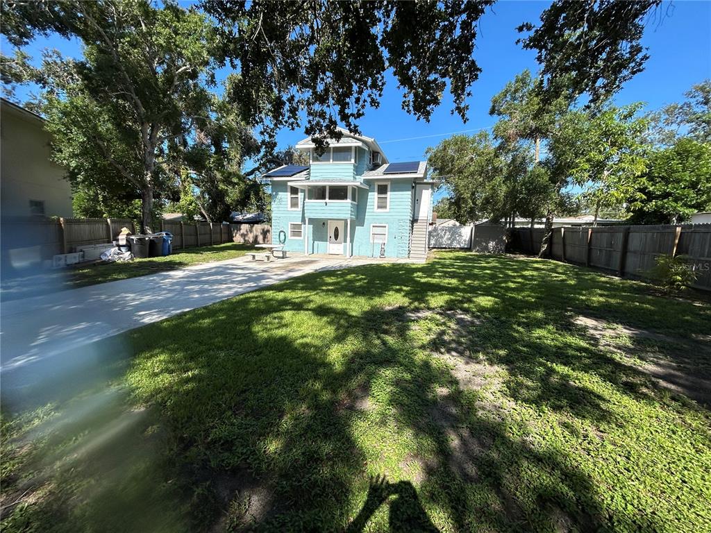 A three-story light blue house with solar panels stands in a large, fenced-in backyard — 2321 TRELAIN DRIVE S, ST PETERSBURG, FL