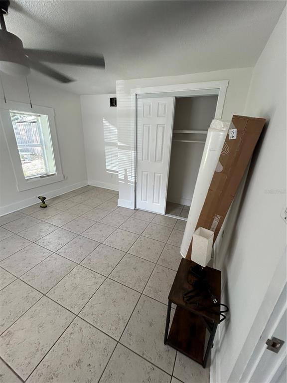 A bedroom features white walls, light-colored tile flooring, a ceiling fan, and a closet — 2321 TRELAIN DRIVE S, ST PETERSBURG, FL