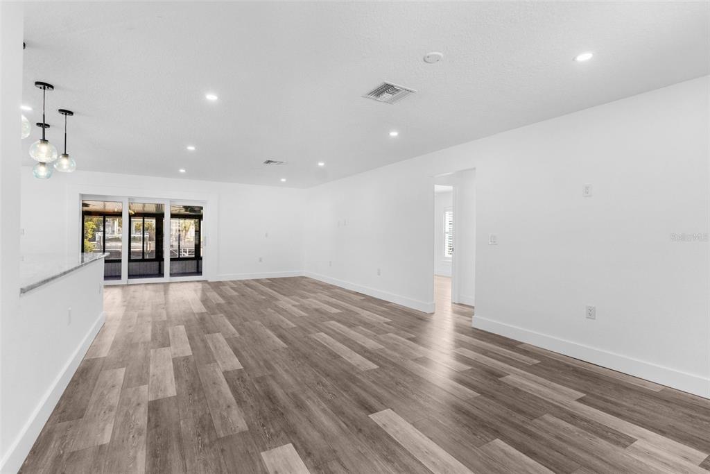 An open-concept living area features white walls, recessed lighting, and wood-look flooring — 4390 6TH ISLE DRIVE, HERNANDO BEACH, FL