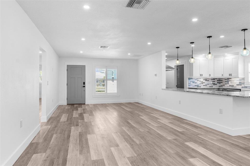 An open-concept living area features light wood-look flooring, white walls, and a modern kitchen — 4390 6TH ISLE DRIVE, HERNANDO BEACH, FL