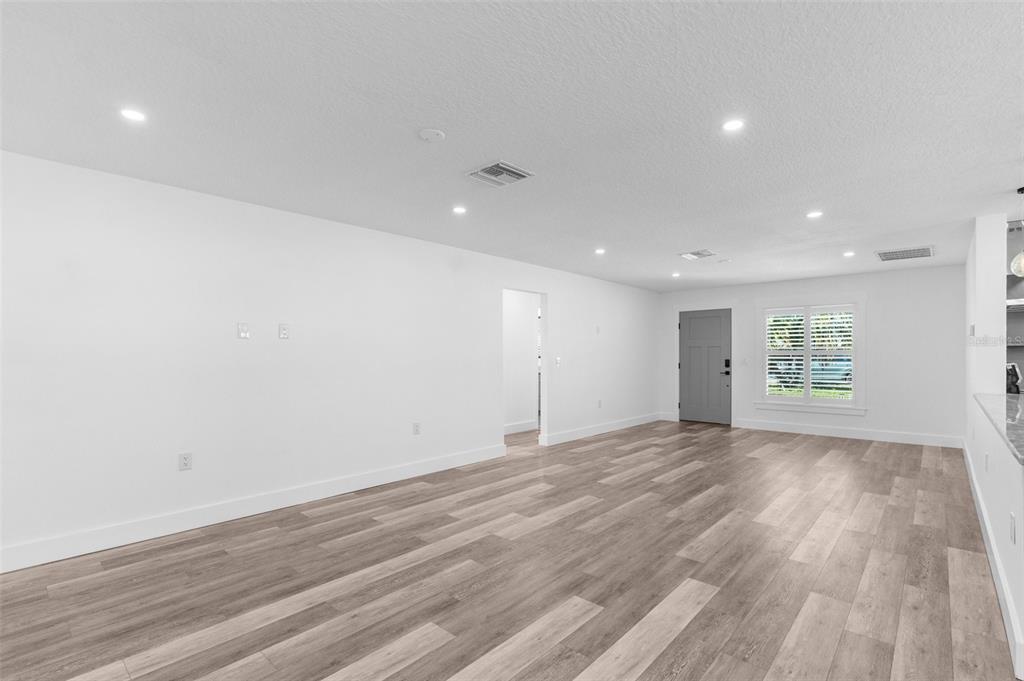 An empty living room with white walls, recessed lighting, and wood-look vinyl plank flooring — 4390 6TH ISLE DRIVE, HERNANDO BEACH, FL