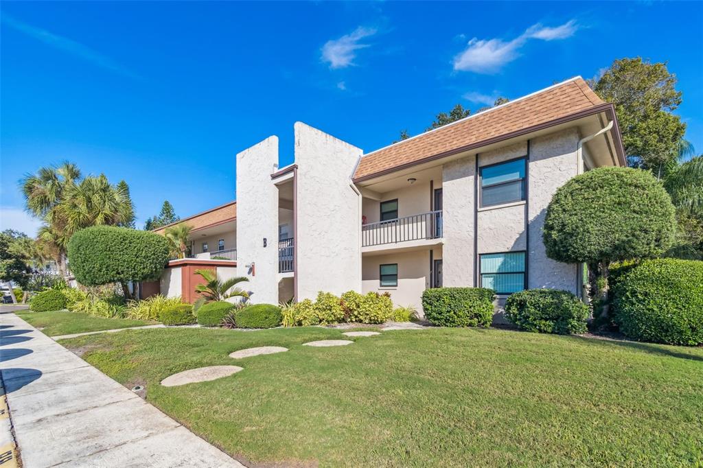A two-story apartment building with a beige stucco exterior and a brown shingled roof — 2750 E BAY DRIVE UNIT 12B, LARGO, FL