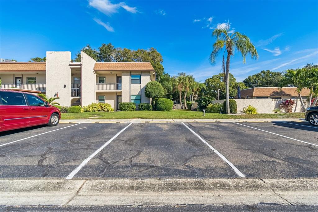 A paved parking lot sits in front of a two-story apartment building with balconies — 2750 E BAY DRIVE UNIT 12B, LARGO, FL