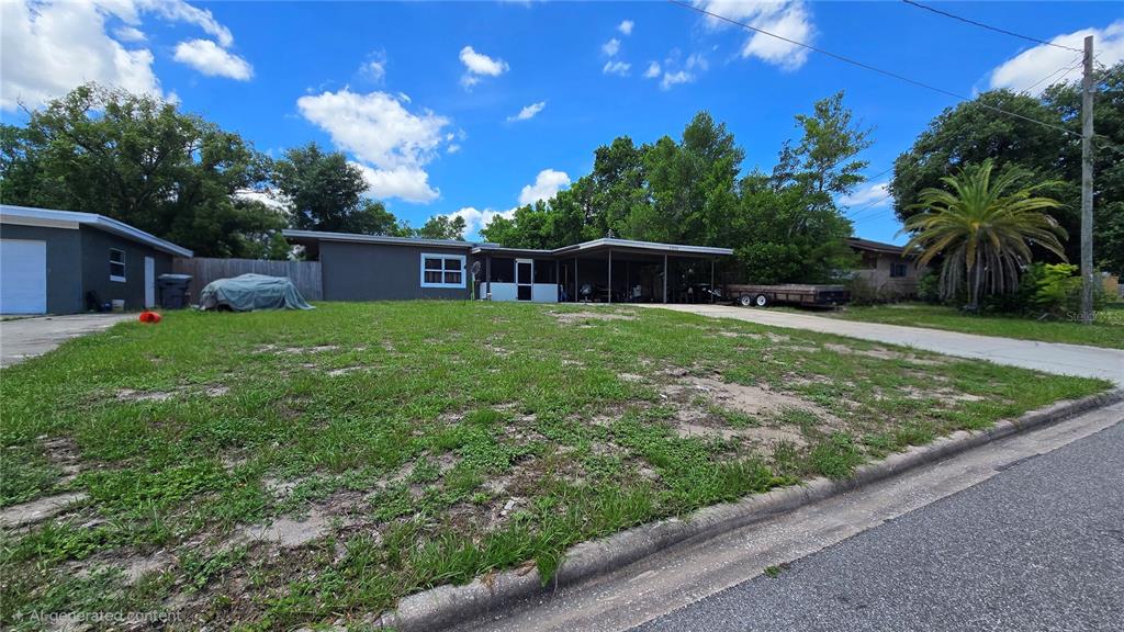 A single-story house with a carport and a large, sparse front lawn under a sky — 5906 JUDY DEE DRIVE, ORLANDO, FL