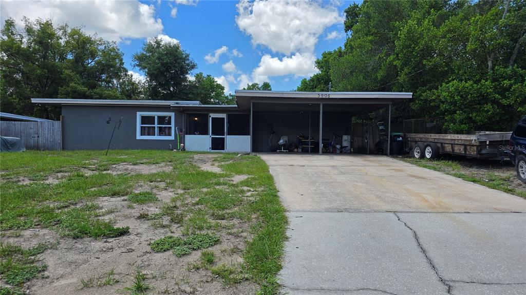 A single-story house with a flat roof, a carport, and a screen-enclosed front porch — 5906 JUDY DEE DRIVE, ORLANDO, FL
