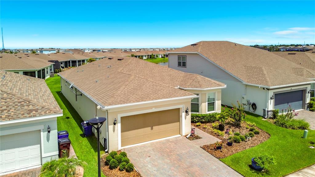 An aerial view shows a suburban house with a tan garage and a paved driveway — 1974 SPRING SHOWER CIRCLE, KISSIMMEE, FL