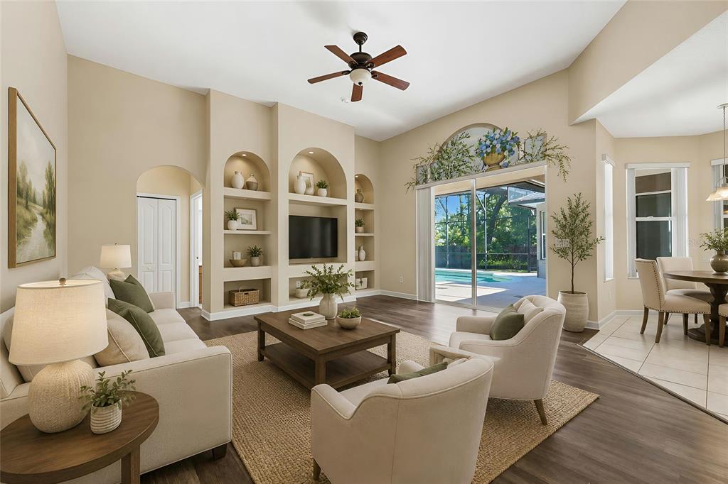 A living room features built-in arched shelving, a television, a ceiling fan, and sliding glass doors — 1200 ALBERTA STREET, LONGWOOD, FL