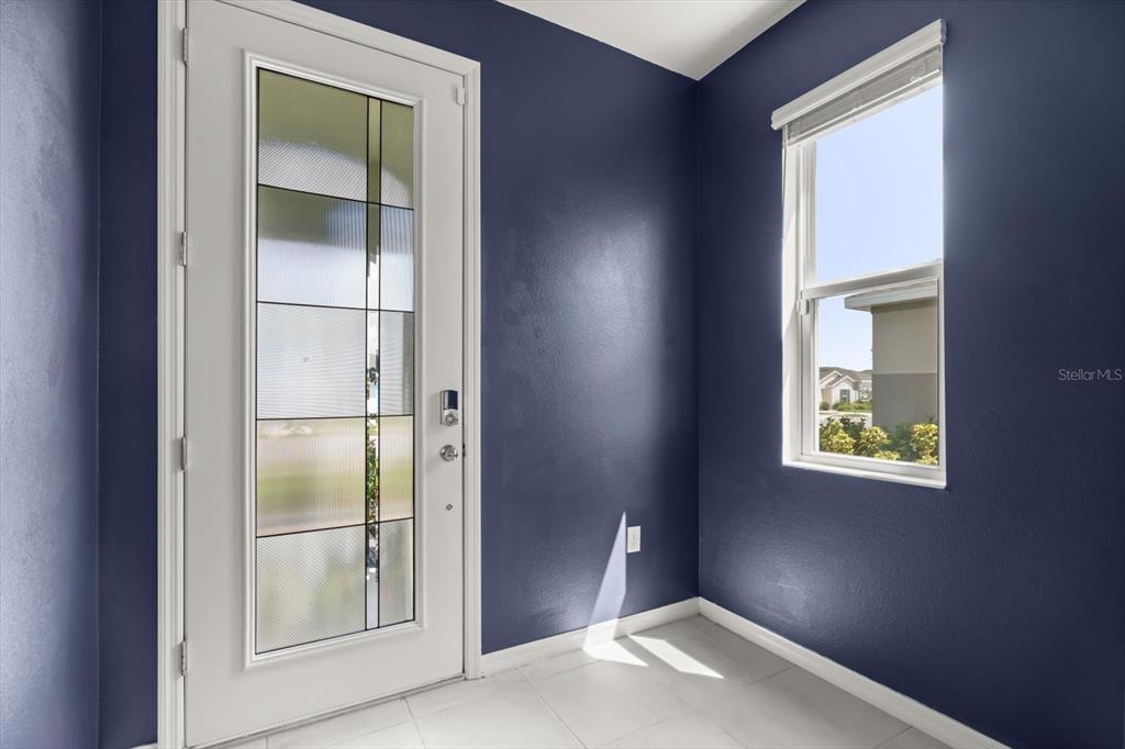 An entryway features dark blue walls, white tile flooring, a glass-paneled door, and a window — 6973 WILSON PASTURE AVENUE, GROVELAND, FL
