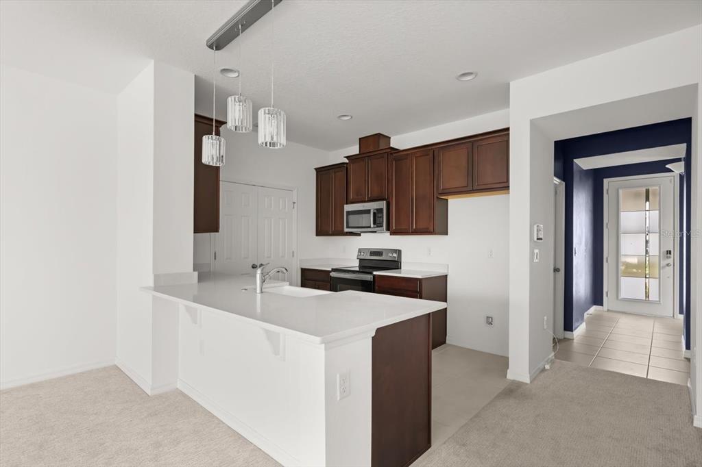 A kitchen features dark wood cabinets, white countertops, a breakfast bar, and pendant lighting — 6973 WILSON PASTURE AVENUE, GROVELAND, FL