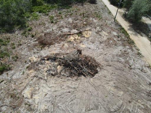 An aerial view shows a cleared, sandy lot with a pile of debris and trees — Y SE 143RD LN, UMATILLA, FL