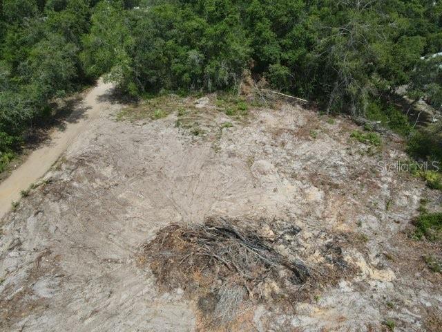 An aerial view shows a cleared, sandy lot bordered by dense trees and a dirt road — Y SE 143RD LN, UMATILLA, FL