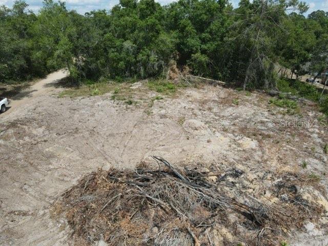 An elevated view shows a cleared, sandy residential lot with a pile of brush — Y SE 143RD LN, UMATILLA, FL