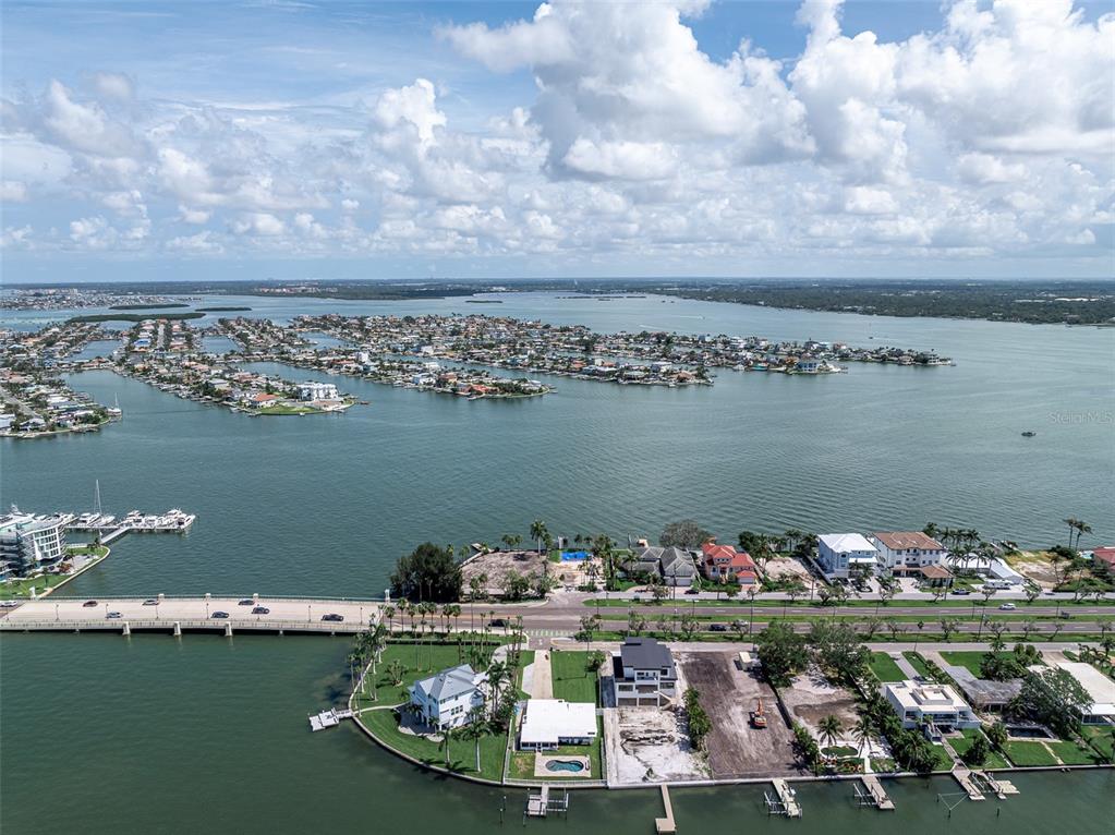 An aerial view shows a coastal town with a bridge, waterways, and sandy beaches — 2 PARADISE LANE, TREASURE ISLAND, FL