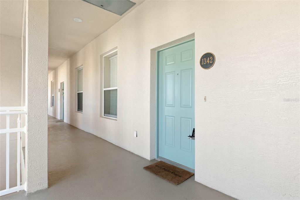 A light blue front door with the number 1342 is situated on a covered outdoor walkway — 15 OCEAN CREST WAY UNIT 1342, PALM COAST, FL