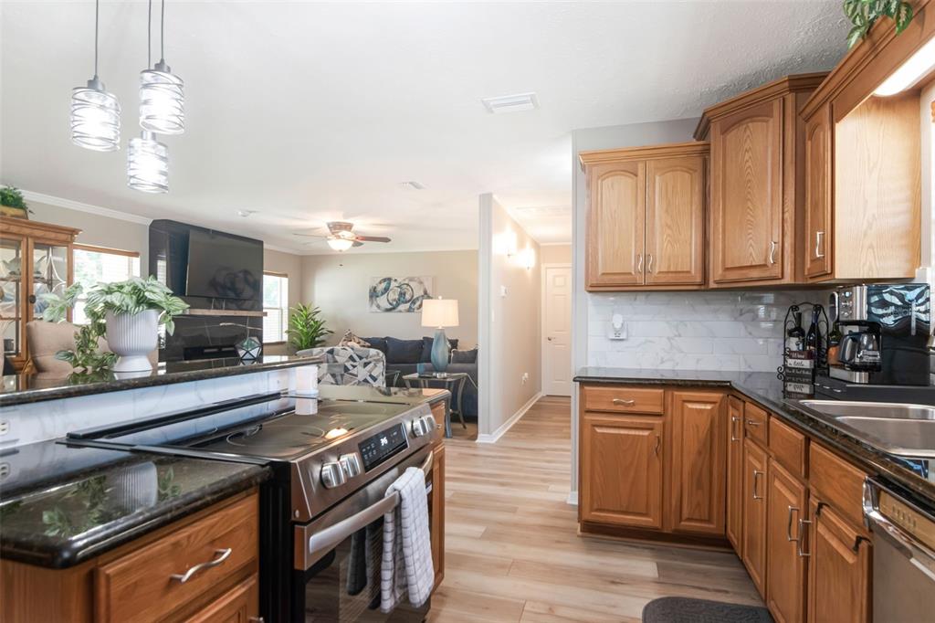 A kitchen with oak cabinets and dark countertops overlooks a living room with a fireplace — 1912 MAY STREET, BRANDON, FL