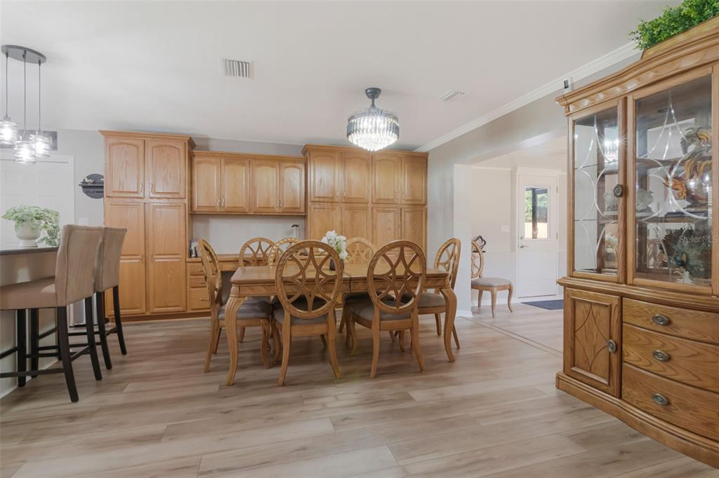 A dining room features light wood flooring, oak cabinetry, and a central chandelier — 1912 MAY STREET, BRANDON, FL