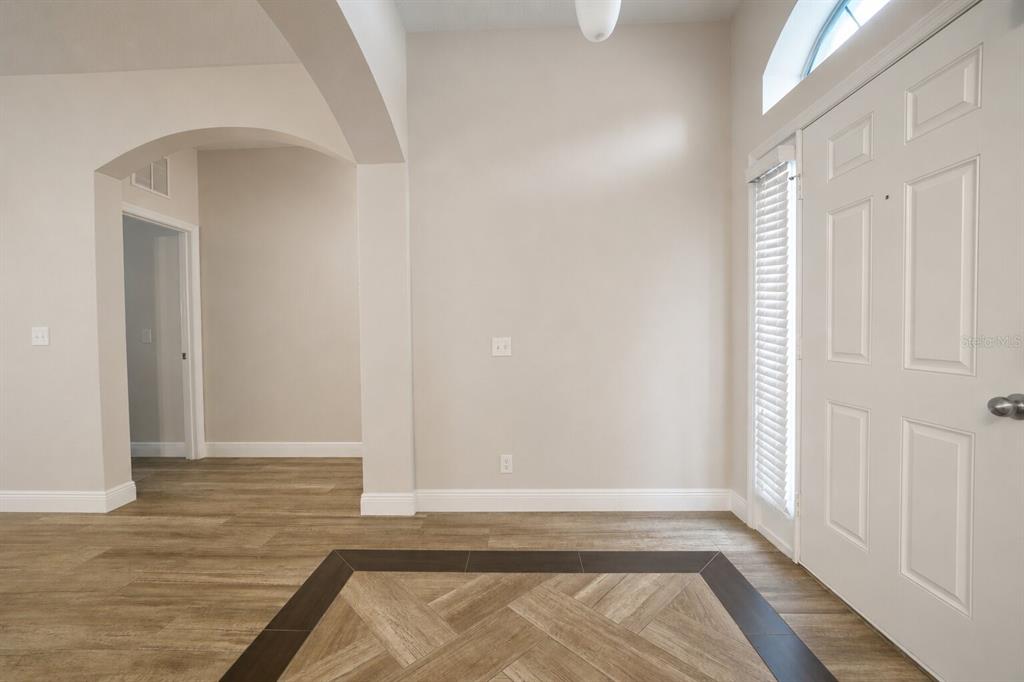 An entryway features wood-look flooring with a dark tile border and a white front door — 1147 DEGRAW DRIVE, APOPKA, FL