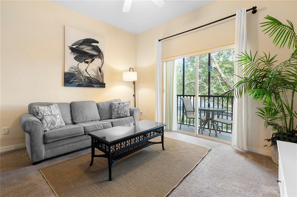 A living room features a gray sofa, a black coffee table, and a sliding glass door — 607 GRAN BAHAMA BOULEVARD UNIT B29/U607, DAVENPORT, FL