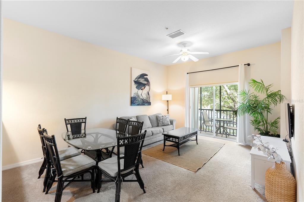 A living and dining area features a glass-top table, gray sofa, and sliding glass doors — 607 GRAN BAHAMA BOULEVARD UNIT B29/U607, DAVENPORT, FL