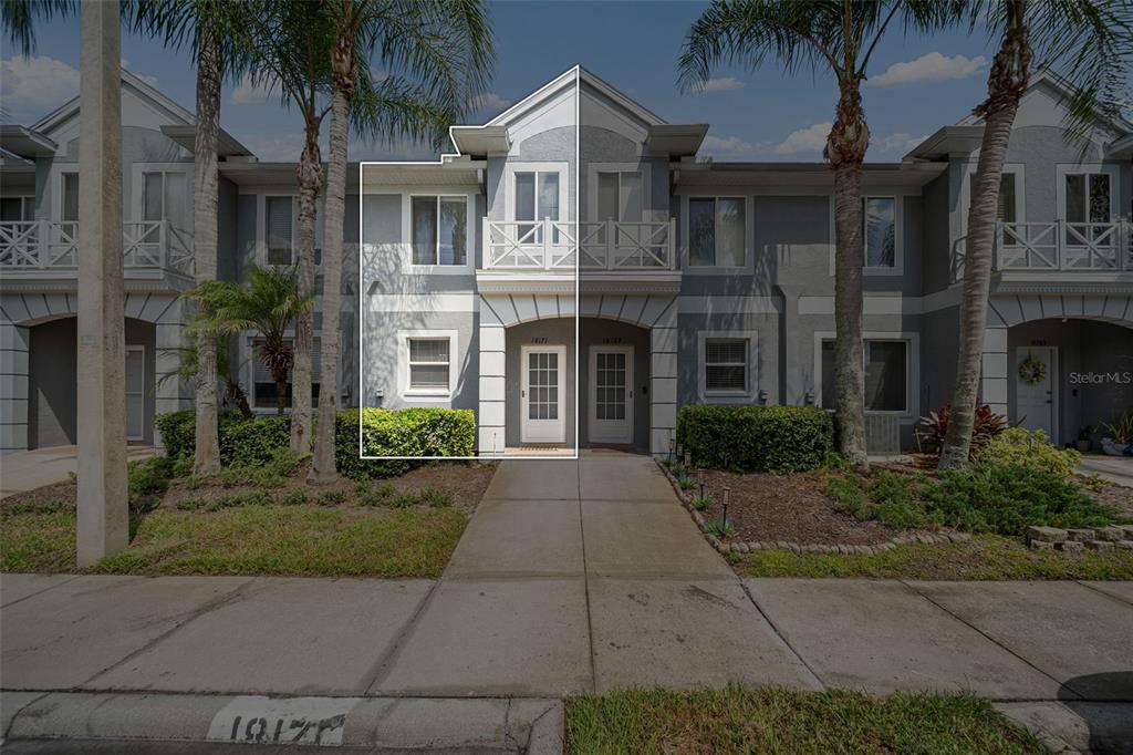 A two-story townhouse exterior with a white-framed entrance and a second-floor balcony — 18171 PARADISE POINT DRIVE, TAMPA, FL