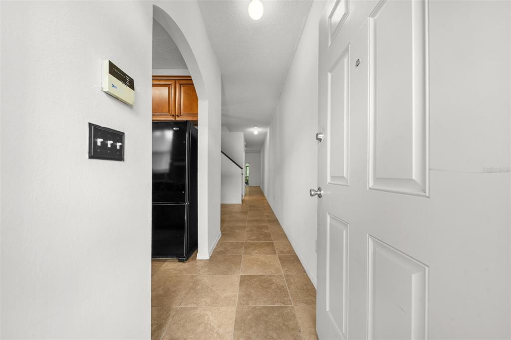 A white door opens into a tiled hallway leading toward a kitchen with dark cabinets — 18171 PARADISE POINT DRIVE, TAMPA, FL
