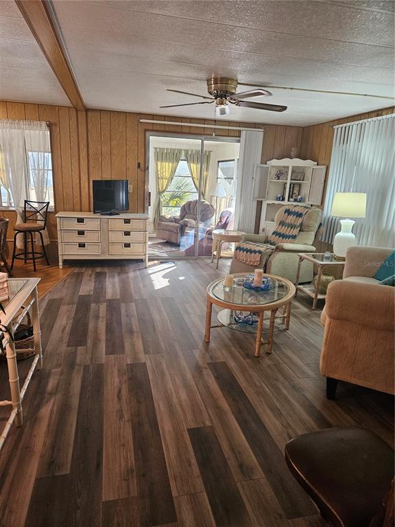 A living room features wood-paneled walls, wood-look flooring, a ceiling fan, and a sliding glass door — 5670 TEAHOUSE ROAD, VENICE, FL