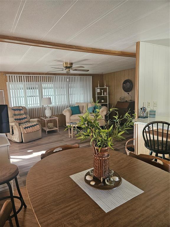 A dining area in the foreground opens into a living room with wood-paneled walls — 5670 TEAHOUSE ROAD, VENICE, FL
