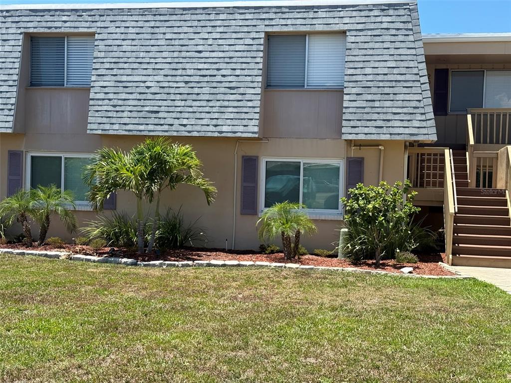 A two-story building exterior with a gray shingled roof, tan walls, and wooden stairs — 1000 APOLLO BEACH BOULEVARD UNIT 204, APOLLO BEACH, FL