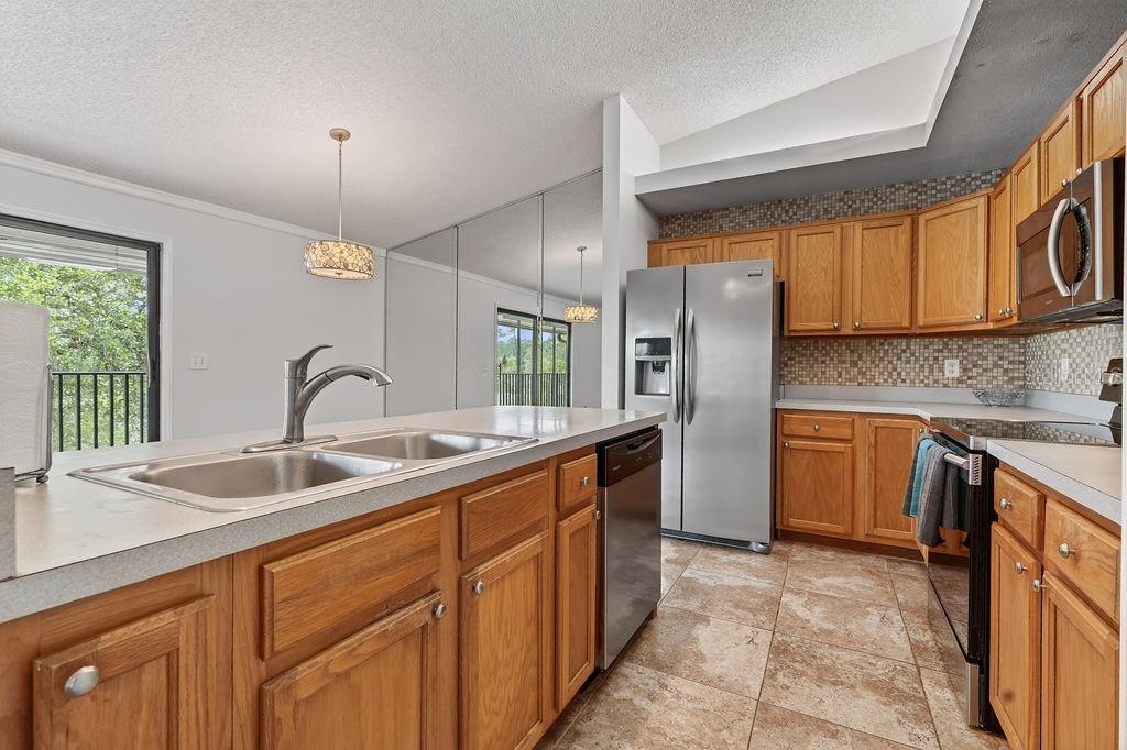 A kitchen features oak cabinets, stainless steel appliances, a double sink, and tiled flooring — 18 TALAVERA COURT UNIT 18, ST AUGUSTINE, FL