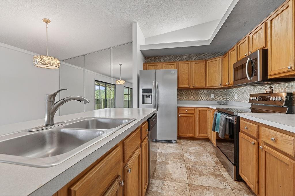 A kitchen features oak cabinets, stainless steel appliances, a double sink, and tiled flooring — 18 TALAVERA COURT UNIT 18, ST AUGUSTINE, FL