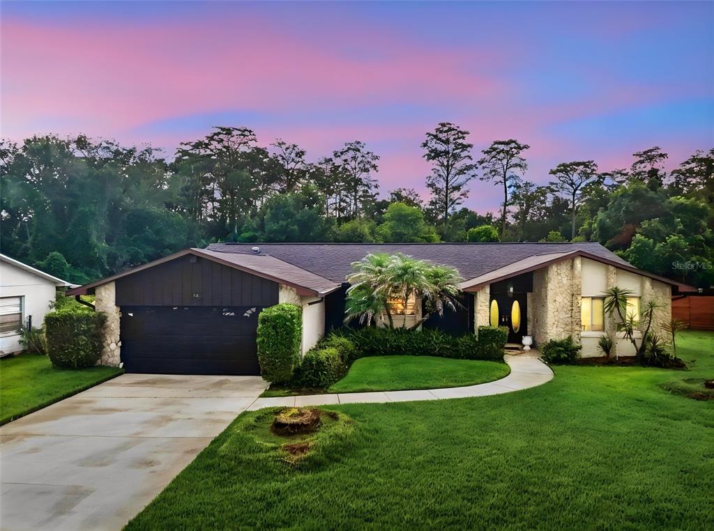 A single-story house with a stone facade, dark wood accents, and a two-car garage — 14 MADEIRA AVENUE, ORLANDO, FL
