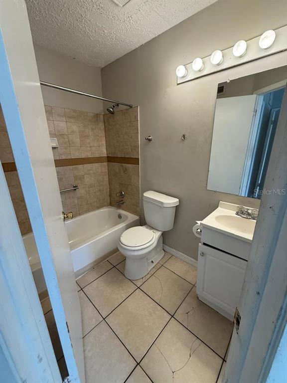 A bathroom features a tiled bathtub, a white toilet, and a vanity with a mirror — 1956 LAKE ATRIUMS CIRCLE UNIT 150, ORLANDO, FL