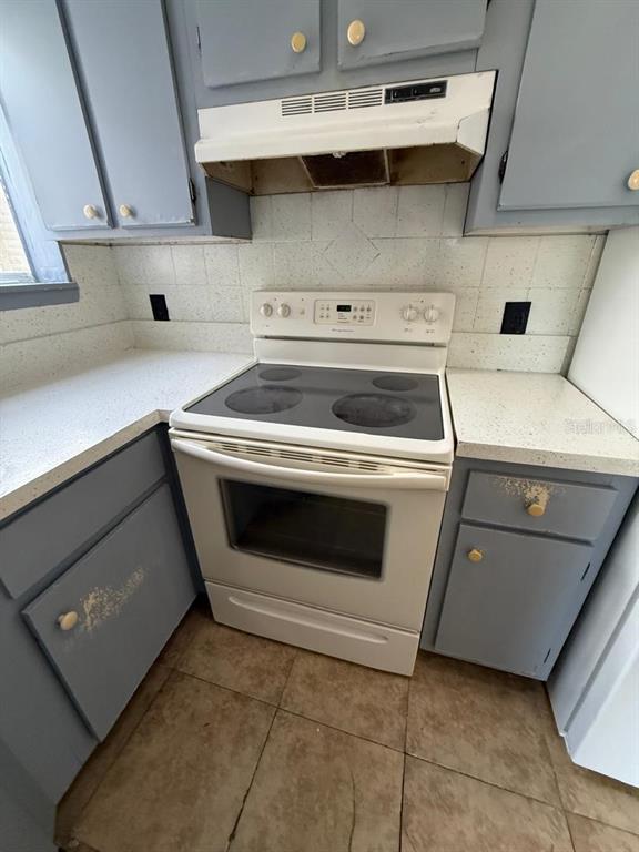 A kitchen features blue cabinets, a white electric stove, and light-colored countertops — 1956 LAKE ATRIUMS CIRCLE UNIT 150, ORLANDO, FL