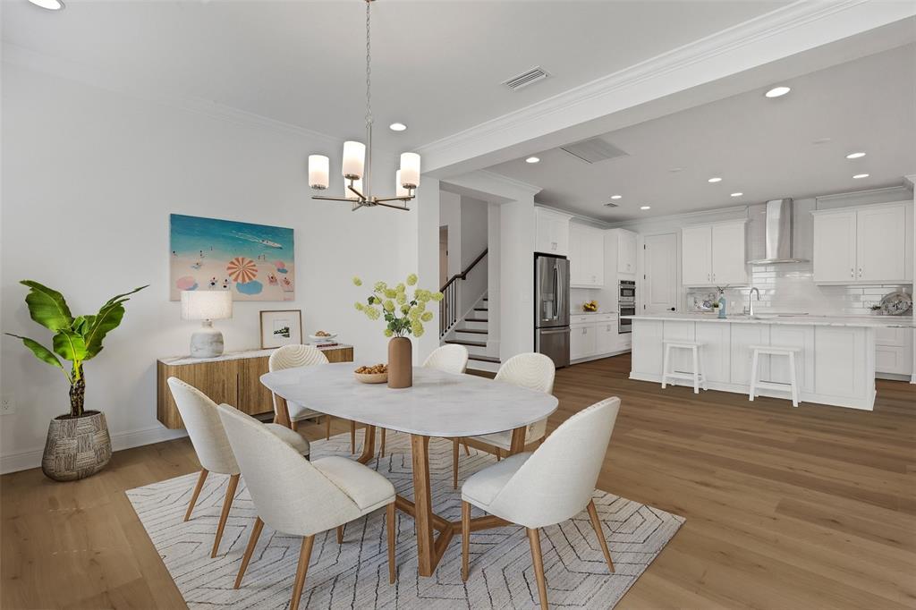 A dining area with an oval table and chairs sits adjacent to a white kitchen — 1669 LUGANO CIRCLE, NOKOMIS, FL