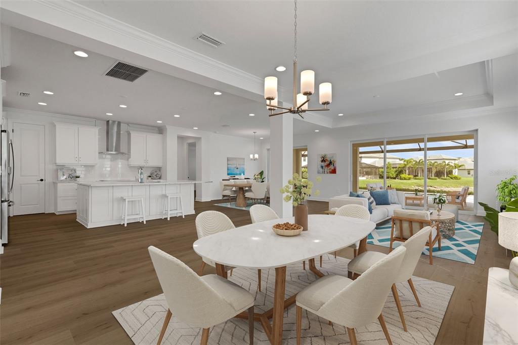 An open-concept living area features a white kitchen, dining space, and a view of the patio — 1669 LUGANO CIRCLE, NOKOMIS, FL