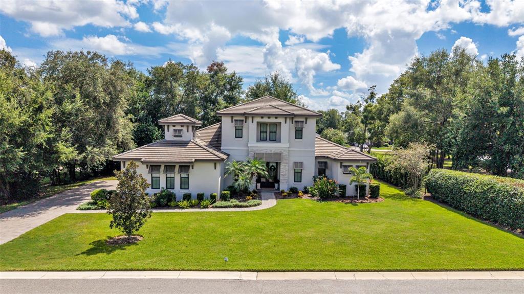 A two-story suburban house with a light-colored stucco exterior, tile roof, and landscaped front yard — 2476 DELPHI CIRCLE, LAKELAND, FL