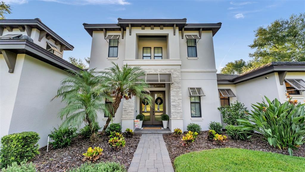A two-story house with a stone-accented entryway, palm tree, and paved walkway — 2476 DELPHI CIRCLE, LAKELAND, FL