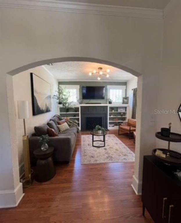 A living room with a fireplace, built-in shelves, and hardwood floors viewed through an arched doorway — 2802 4TH AVENUE W, BRADENTON, FL
