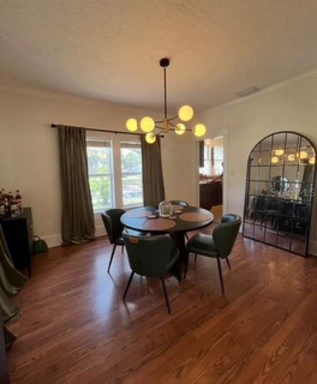 A dining room features a round table, four green chairs, a modern chandelier, and a large mirror — 2802 4TH AVENUE W, BRADENTON, FL