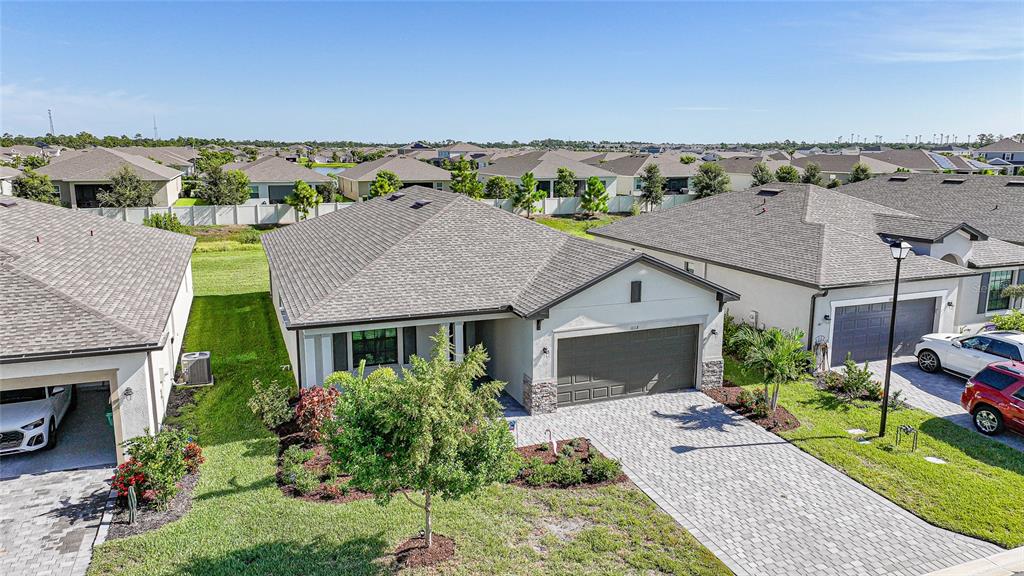 An aerial view shows a single-story suburban house with a paved driveway and garage — 1608 SADDLEWOOD CIRCLE, PORT CHARLOTTE, FL