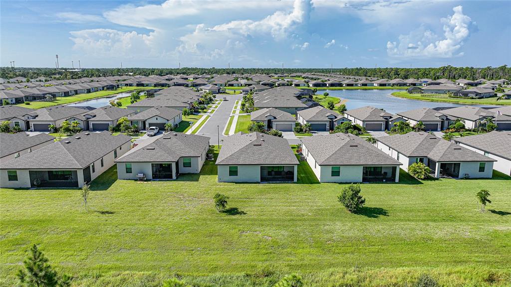 An aerial view shows a suburban neighborhood with houses, a street, and a retention pond — 1608 SADDLEWOOD CIRCLE, PORT CHARLOTTE, FL